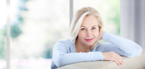 Beautiful business woman smiling friendly and looking in camera near the window in office. Happy woman's face closeup. Selective focus.