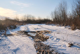Fototapeta  - The country road is covered with the first snow with a broken track from the wheels of cars.