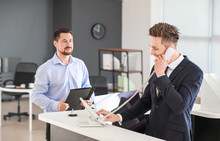 Male Receptionist Talking On Phone In Office