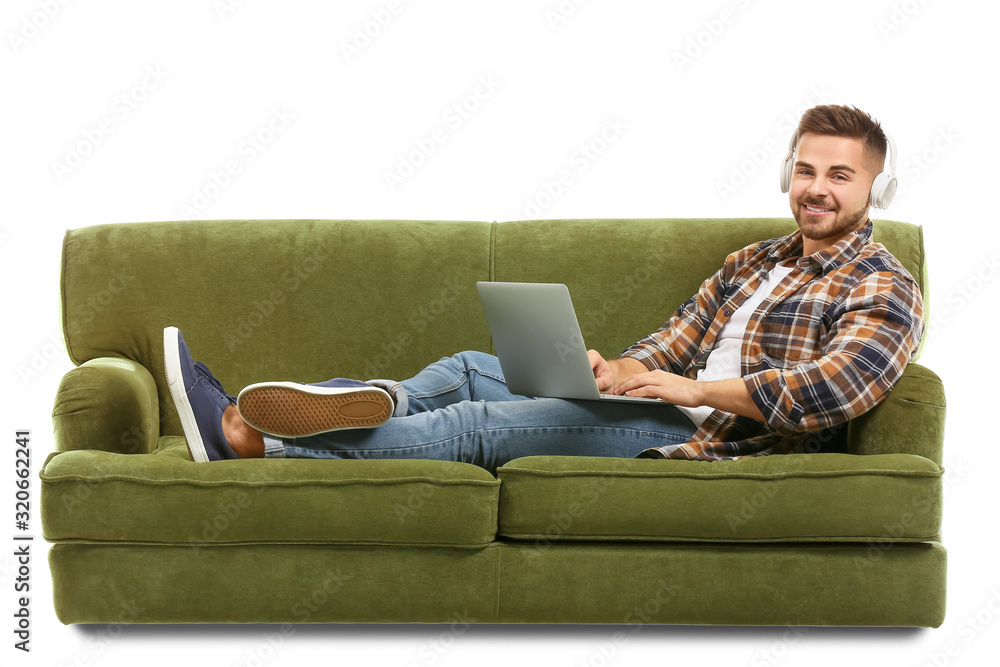 Young man listening to music while sitting on sofa against white background