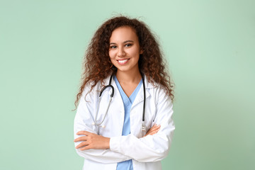 Sticker - Young African-American doctor on color background