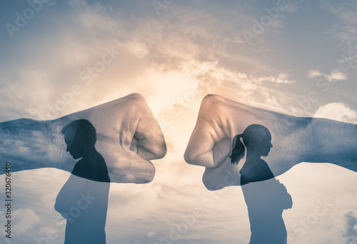 Fotografía Couple with back turned away from each other with fist clashing in the background