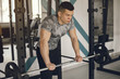 © hetmanstock2 - Sports man in the gym. A man performs exercises. Guy in a gray t-shirt