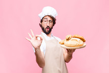 Young Crazy Baker Man Holding Bread Against Pink Wall