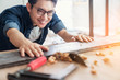 © whyframeshot - smart attractive handy glasses asian male craftman or interior designer focus wood working at site constrution home interior design house renovation and improvement concept