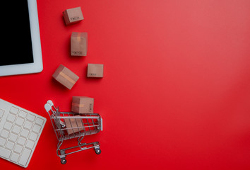 Online shopping,paper boxes,small shopping cart,smartphone and keyboard against red background