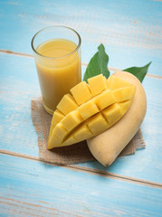 Wall Mural - Mango juice in a glass with mango slice on wood