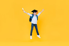 Schoolboy With Graduate Cap Smiling And Jumping On Yellow Background