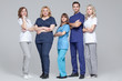 © satyrenko - Successful team of medical doctors are looking at camera while standing on grey background