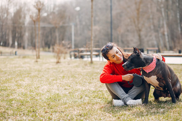 Sports woman in a red sweater. Woman in a summer park. Lady with a dog