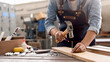 © MIND AND I - Carpenter working with equipment on wooden table in carpentry shop. woman works in a carpentry shop.