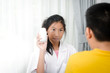 © nuiiko - Asian girl pharmacist explaining something to a preteen boy, holding blisters with pills, health care concept.