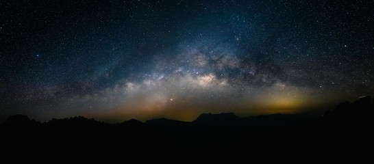 Wall Mural - night landscape with colorful milky way and yellow light at mountains.