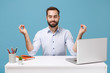 Relaxed young bearded man in light shirt sit work at desk with pc laptop isolated on blue background. Achievement business career lifestyle concept. Holding hands in yoga gesture, relaxing meditating.