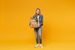 © ViDi Studio - Smiling young woman in denim clothes isolated on yellow orange wall background. Delivery service from shop or restaurant concept. Hold brown craft paper bag for takeaway mock up with food products.