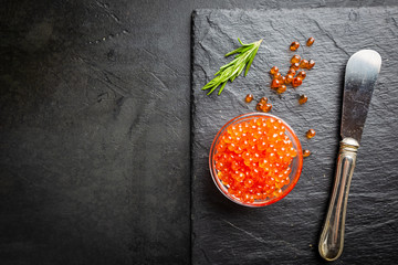 Wall Mural - Delicious red caviar on black slate background, top view