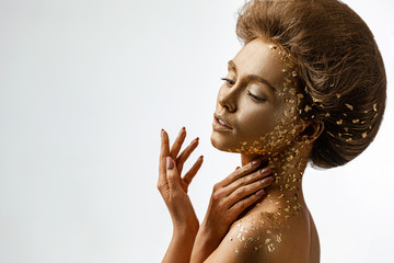 Wall Mural - Fashion art portrait of model girl with holiday golden shiny professional makeup. woman with gold metallic body and hair. Gold glowing skin. Hairstyle. copy space