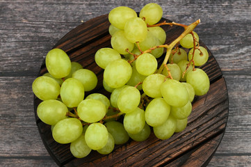 Sticker - Green grapes on a wooden background. Flat lay. view from above. Place for writing. Juicy bunch of grapes on a wooden background.