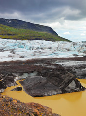 Canvas Print -  Blue ice covered ground black volcanic ash