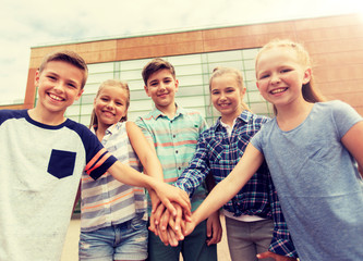 Canvas Print - primary education, friendship, childhood and people concept - group of happy elementary school students with hands on top outdoors