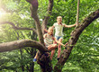 © Syda Productions - friendship, childhood, leisure and people concept - two happy girls climbing up tree and having fun in summer park