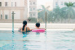 © makistock - Mother and son in outdoor swimming pool with city view.