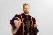 handsome king with crown showing hand isolated on grey
