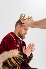 Wall Mural - cropped view of man putting crown on king with praying hands on grey background