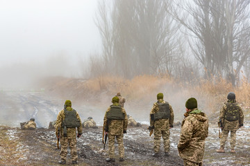 Privates and officers in camouflage and body armor shoot Kalashnikovs at targets in the shooting range from a Kalashnikov assault rifle.