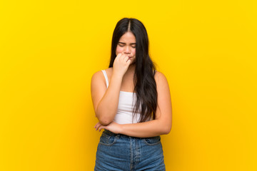 Wall Mural - Young teenager Asian girl over isolated yellow background having doubts