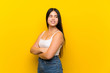 © luismolinero - Young teenager Asian girl over isolated yellow background with arms crossed and happy