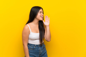 Wall Mural - Young teenager Asian girl over isolated yellow background shouting with mouth wide open to the lateral