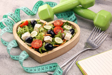 Authentic Fresh Salad In A Wooden Heart Shaped Cup With Dumbbells Excercise Equipment, Measuring Tape On Table. Healthy Lifestyles, Good Health
