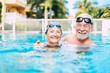 © Daniel - couple of cute seniors and pensioners in the water of the pool having fun and enjoying together - two mature people in love looking at the camera - doing exercise and training together smiling