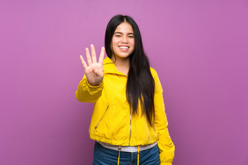 Wall Mural - Young teenager Asian girl over isolated purple background happy and counting four with fingers