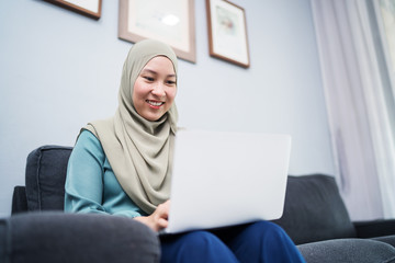 Wall Mural - Female muslim using laptop at home environment.