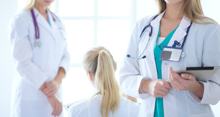 Wall Mural - Portrait of three confident female doctors standing with arms crossed at the medical office.