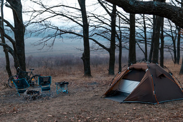 equipped camp in the forest. camping tent and portable chairs and aluminum table. cold autumn day. c