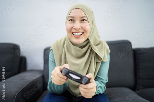 Fotografía Beautiful muslim woman playing console games at her couch.