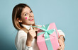Smiling teen kid girl celebrate valentines day holding a big pink present gifts box for birthday happy pointing at it