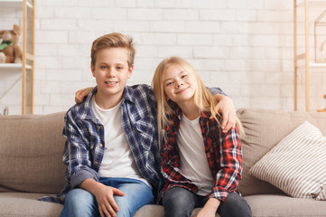 Brother And Sister Embracing Smiling Sitting On Couch At Home