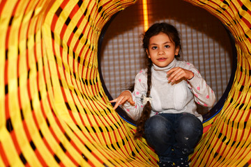 Wall Mural - little beautiful girl plays on children's simulators in a children's play area