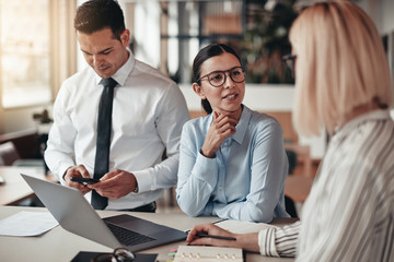 Wall Mural - Two smiling businessswomen talking together at an office table