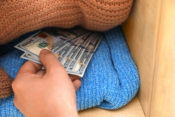 Wall Mural - Man hiding money between clothes in wardrobe, closeup. Financial savings