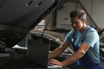 Wall Mural - Mechanic with laptop doing car diagnostic at automobile repair shop