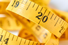 Yellow Color Centimeter With Black Figures For Measurement Of Length And Width On A White Background. Measuring Tape Of The Tailor For You Design. Closeup, Selective Focus