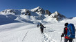 © serghi8 - In winter, some hikers walk the snowy valley at the Lucomanio pass in Switzerland.