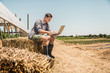 © MACO - Young farmer in the fields with laptop, checking his crops. Laurel, Montana, USA