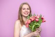 © Богдан Маліцький - young beautiful girl with a bouquet of flowers on a colored pink background, a woman holds tulips and smiles