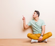 © kues1 - young arabian man standing and pointing to object on copy space, rear view sitting on the floor